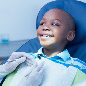 Child in blue shirt smiling at pediatric dentist during checkup