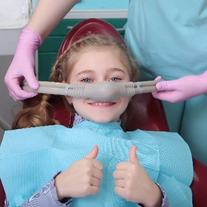 Girl with nasal mask smiling and giving thumbs up