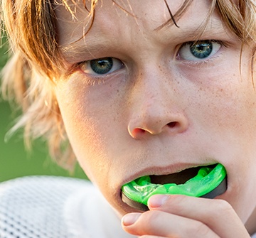 Preteen boy placing sports mouthguard