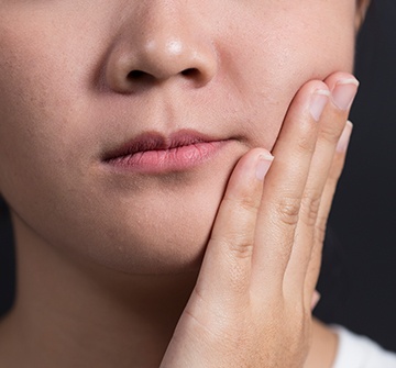 Closeup of child in need of emergency dentistry holding cheek