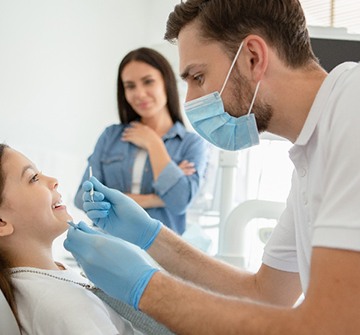 Pediatric emergency dentist examining child's teeth