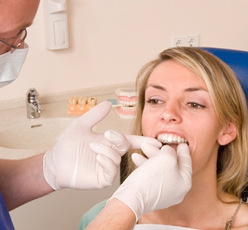 A dentist inserting an Invisalign aligner into a female patient’s mouth