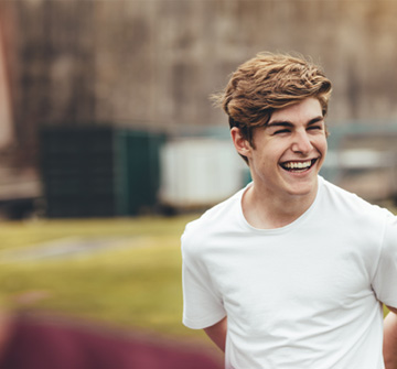 Teen in white shirt smiling outside
