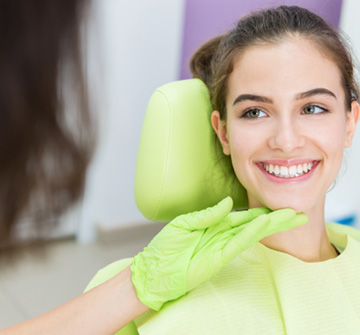 Orthodontist looking at smiling teen's teeth