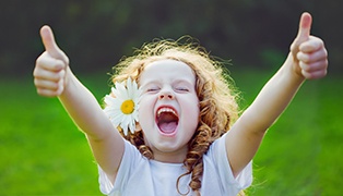 Laughing little girl giving thumbs up