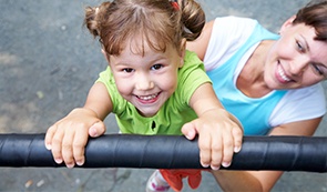 Little girl playing on playground after dentistry for toddlers visit