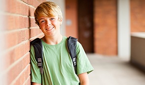 Preteen boy leaning against wall after dentistry for children visit