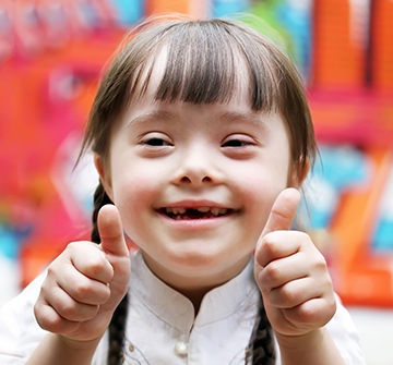 Little girl giving two thumbs up after special needs dentistry visit