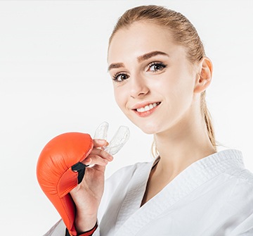 Teen girl wearing boxing gloves holding sports mouthguard