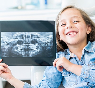 Toddler holding up her dental x-rays