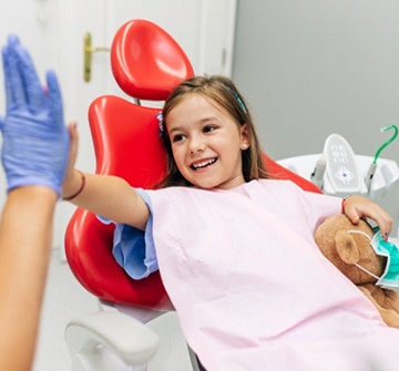 Girl high-fives her Pelham dentist for children after tooth-colored filling treatment