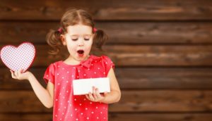 Little girl opening Valentine's Day gift from Pelham dentist for kids