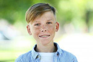 Smiling young boy with orthodontic treatment outside