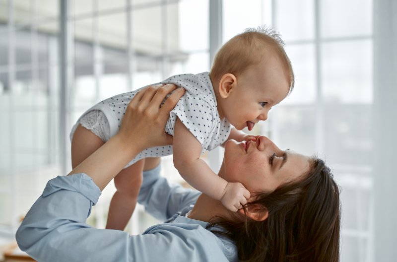 Smiling mom holding up baby