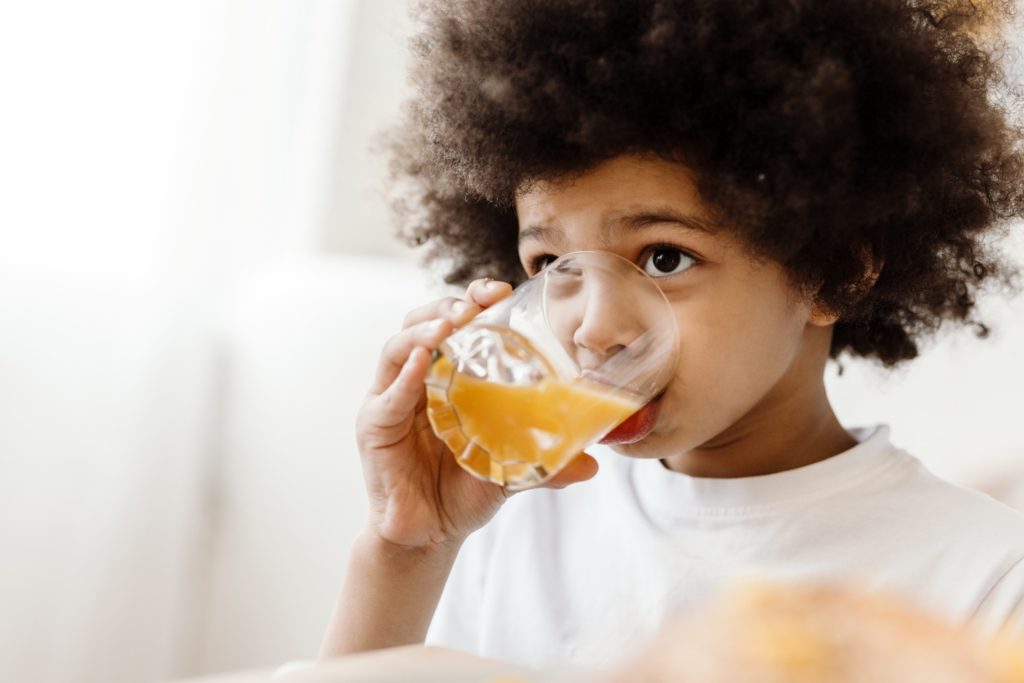 Closeup of child drinking orange juice