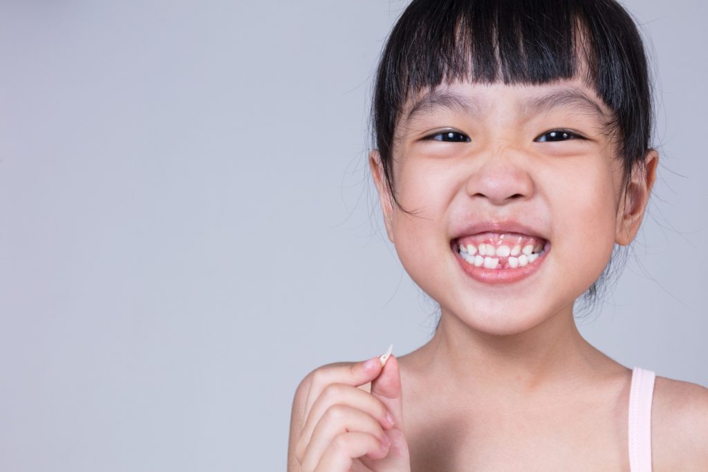 Closeup of child holding baby tooth