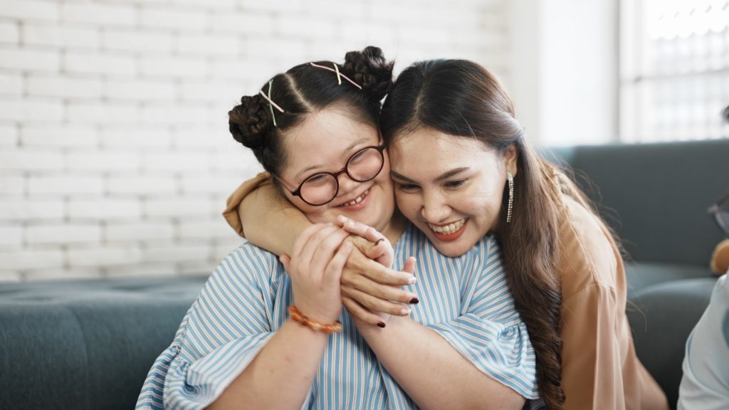 Mother and daughter hugging and smiling in apartment