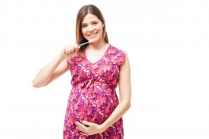 Pregnant woman brushing to maintain optimal oral health