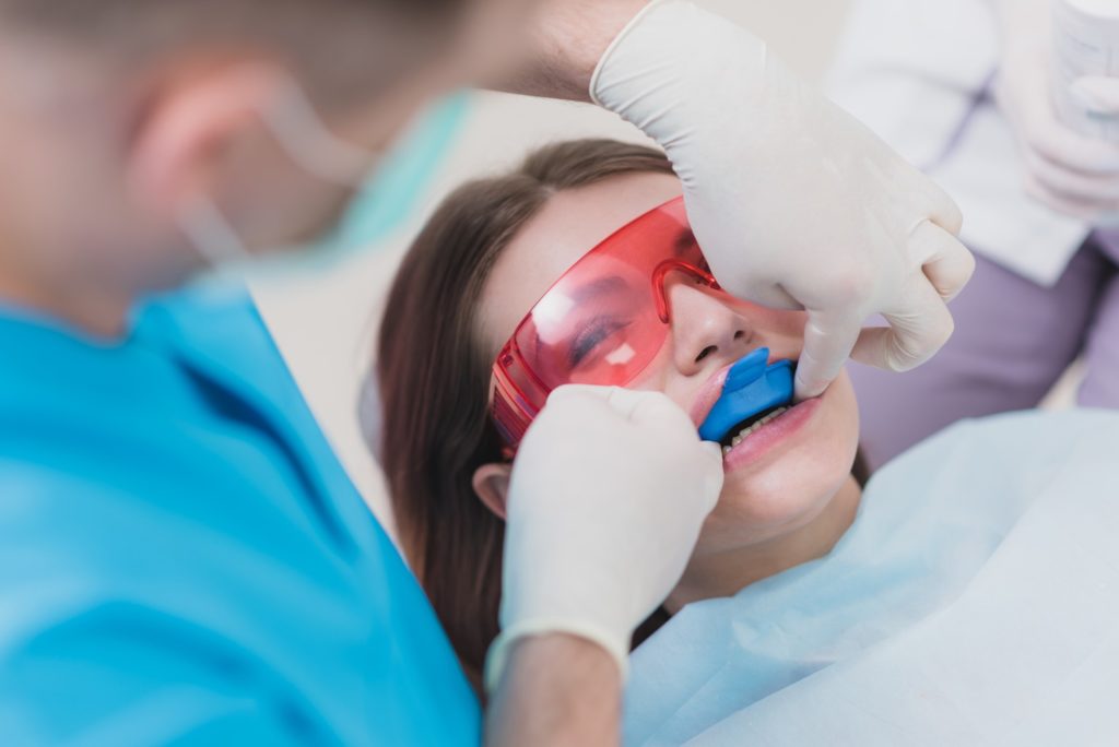 Pediatric dentist conducting fluoride treatment for young girl