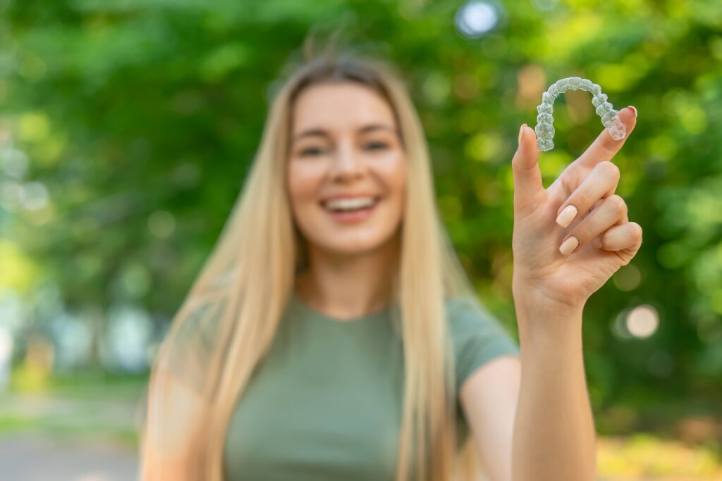 Teen girl smiling while holding clear aligner
