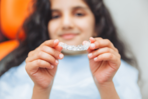 a teen smiling and holding their Invisalign